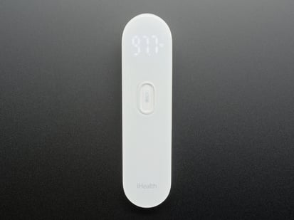 White no touch thermometer shown laying flat and displaying a temperature