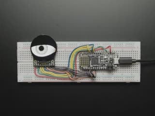 Video of a round TFT display assembled onto a breadboard with a microcontroller. The TFT shows a blinking eyeball animation.